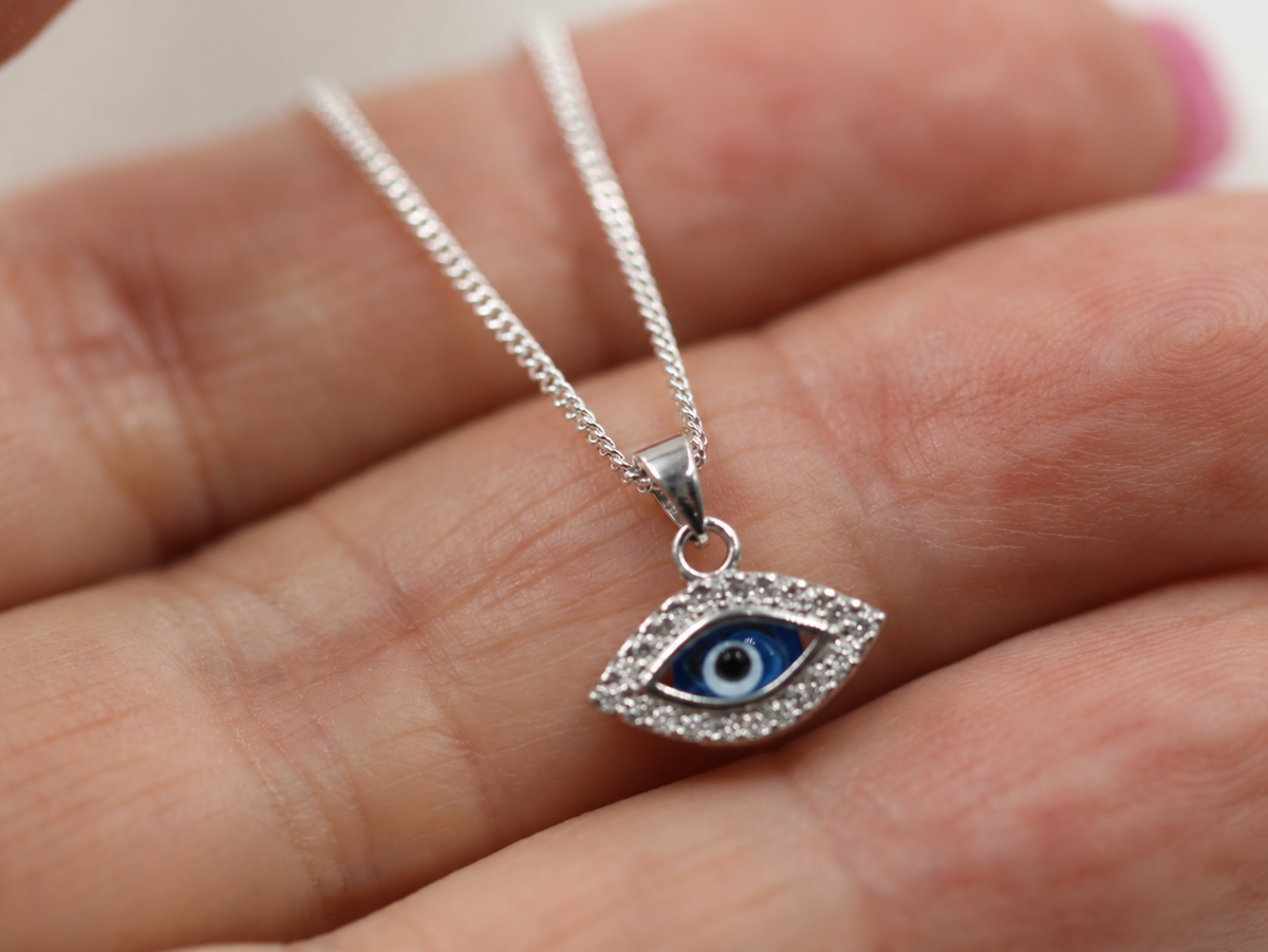 Small sterling silver evil eye nazar pendant shown on a hand for scale
